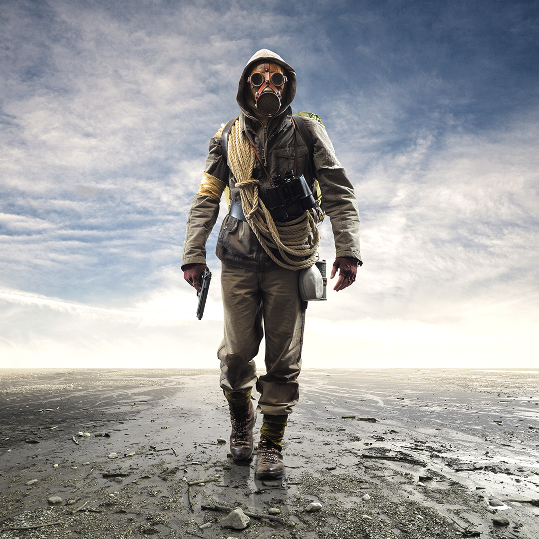 Person in various survival gear in a post-apocalyse wasteland.