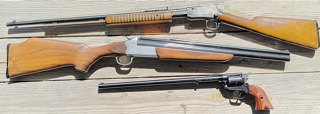 Three guns on a wood background.