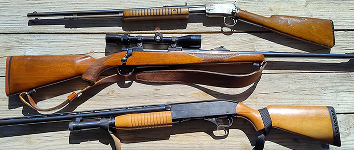Three long guns on a wood background