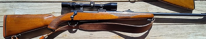 Bolt-action hunting rifle on wood background.