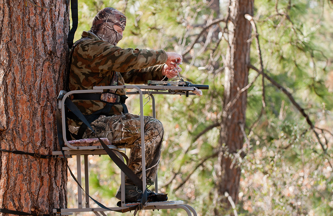 deer hunter wearing camo sitting in tree stand