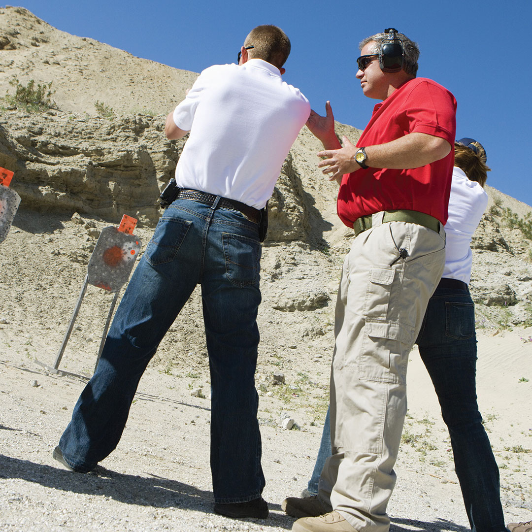 Student at the outdoor shooting range getting advice from a firearms instructor.